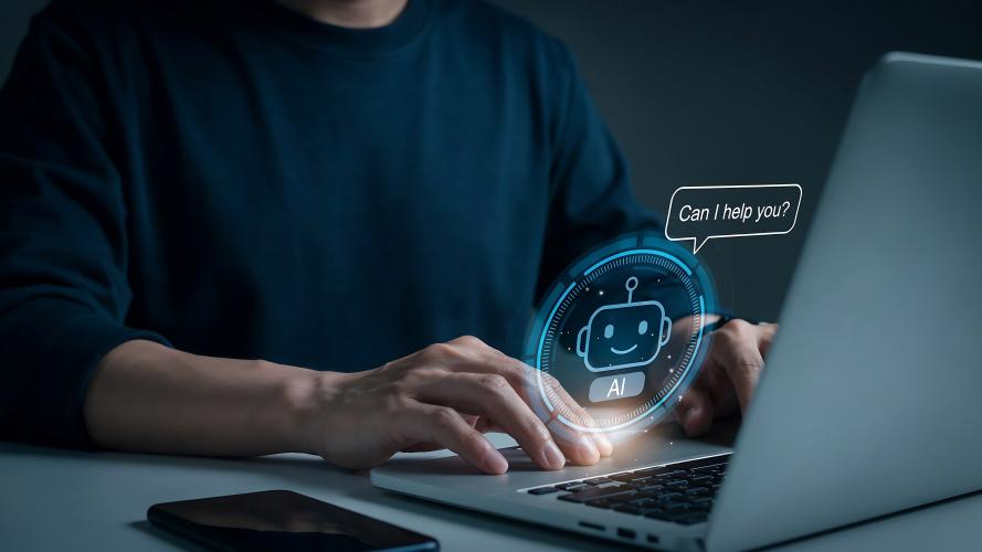 A person at a computer. A little digital robot is hovering near his fingers.